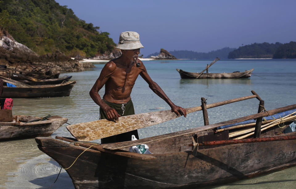 In this Sunday, Feb. 9, 2014 photo, Maali, an elderly Moken man, nomads of the sea, smokes a pipe as he adjusts a paddle on his canoe on Island 115 in Mergui Archipelago, Myanmar. The Moken group of several families are spending 10 days hunting for squid and whatever else they can collect before returning to their village on another island toward Myanmar’s southwestern coast with a lacework of 800 islands, what is known as the Lost World. Isolated for decades by the country’s former military regime and piracy, the Mergui archipelago is thought by scientists to harbor some of the world’s most important marine biodiversity and looms as a lodestone for those eager to experience one of Asia’s last tourism frontiers before, as many fear, it succumbs to the ravages that have befallen many of the continent’s once pristine seascapes. (AP Photo/Altaf Qadri)