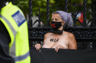 A police stands near a climate activist who locked herself topless against the railings of the Houses of Parliament, during an Extinction Rebellion (XR) protest, in London, Thursday, Sept. 10, 2020. (AP Photo/Alberto Pezzali)