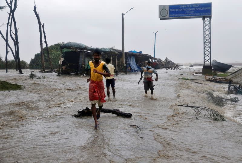 FILE PHOTO: People run through a waterlogged road due to rising sea level ahead of Cyclone Yaas at Digha