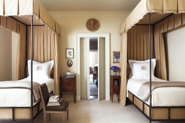 bedroom’s with matching iron beds with canopies and curtains of a cotton silk and an antique side tables are italian and french, and the chair and a double door opening out and a wooden medallion figure over it