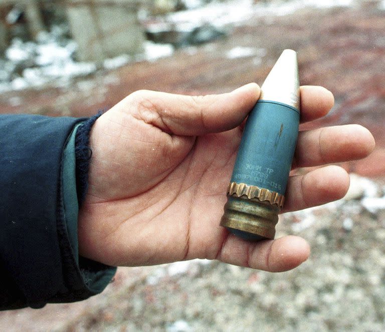 ARCHIVO - Un miembro de un equipo de radiación sostiene un proyectil perforante de 30 mm que contiene uranio empobrecido, utilizado por la OTAN durante los ataques aéreos sobre Bosnia en 1995, que fue encontrado en una antigua fábrica militar en el suburbio de Vogosca, cerca de Sarajevo, 15 de enero de 2001. (AP Photo/Hidajet Delic, Archivo)