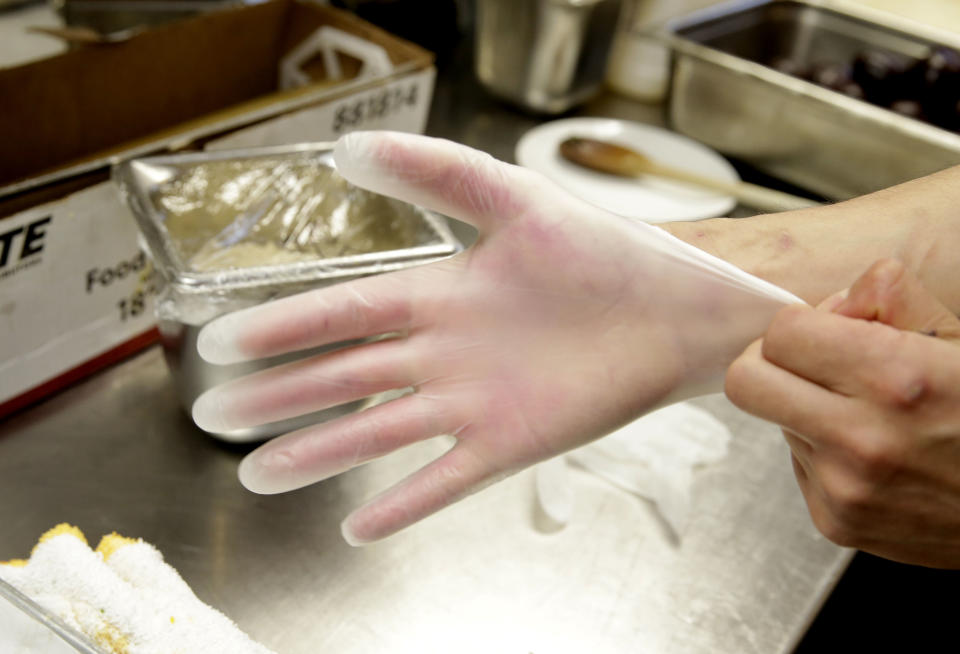 Luis Escamilla puts on gloves before working with food at the Hock Farm Restaurant in Sacramento, Calif. at the Hock Farm restaurant in Sacramento, Calif. Under a bill signed last year by Gov. Jerry Brown, chefs and bartenders in California must keep bare hands off food going straight to the plate or the drink glass, and must use gloves or kitchen utensils such as tongs. California, where the law took effect Jan. 1 and will begin enforcement starting in July, will join 41 other states banning bare-hand contact with ready-to-eat food. In February,after receiving a petition from bartenders calling for an exemption for the "disposable glove law" the law's author, Assemblyman Richard Pan, D-Sacramento, a pediatrician, has introduced a bill to repeal the new regulation and revisit the entire issue.(AP Photo/Rich Pedroncelli)