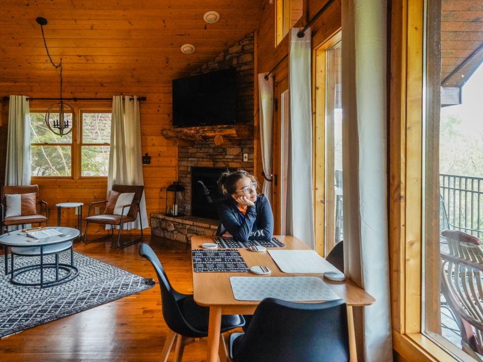 The author sits at a table in the cabin looking out the floor-to-ceiling windows to the right.