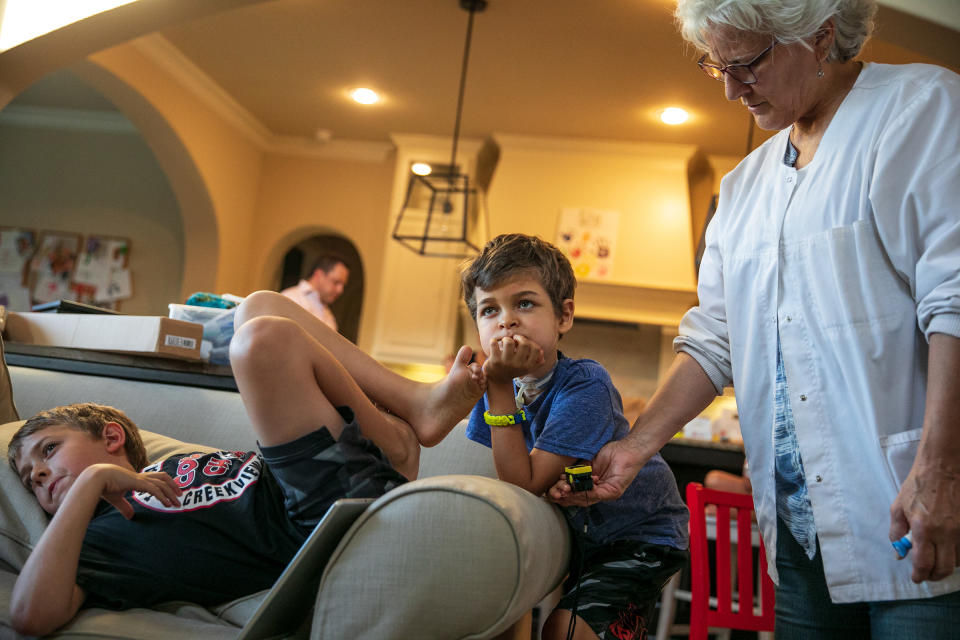 Caroline Casanova, LVN, one of Braden's nurses, checks his pulse and oxygen levels as he watches TV with his brother. | Ilana Panich-Linsman for TIME