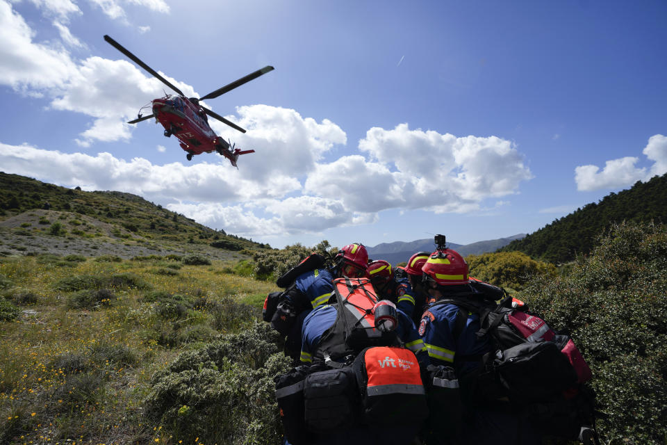 Firefighters of the 1st Wildfire Special Operation Unit take cover as an helicopter takes off after leaving them in a drill near Villia village some 60 kilometers (37 miles) northwest of Athens, Greece, Friday, April 19, 2024. Greece's fire season officially starts on May 1 but dozens of fires have already been put out over the past month after temperatures began hitting 30 degrees Celsius (86 degrees Fahrenheit) in late March. This year, Greece is doubling the number of firefighters in specialized units to some 1,300, adopting tactics from the United States to try and outflank fires with airborne units scrambled to build breaks in the predicted path of the flames. (AP Photo/Thanassis Stavrakis)