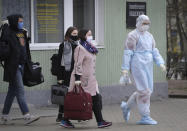 A medical worker wearing a protective suit accompanies students into an ambulance in Minsk, Belarus, Tuesday, April 21, 2020. The World Health Organization is urging the government of Belarus to cancel public events and implement measures to ensure physical and social distancing amid the growing coronavirus outbreak. (AP Photo/Sergei Grits)