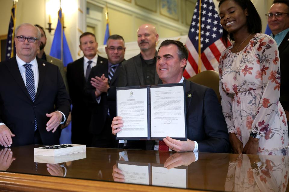 Oklahoma Gov. Kevin Stitt holds up an executive order in the Blue Room at the state Capitol in Oklahoma City, Wednesday, Dec. 13, 2023.