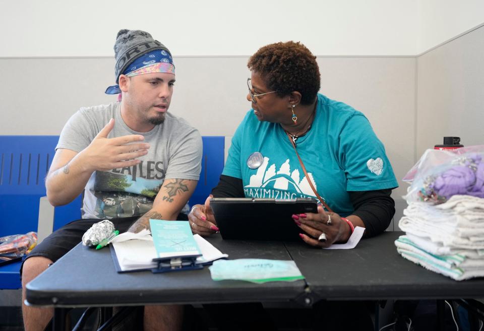 Arlene Carrie, right, a volunteer with Maximizing Hope, helps Chris Harris get a bus pass at Maximizing Hope's laundromat event last week. The laundry events have helped caseworkers connect with homeless people who need help, to find out what they need to get back into housing.