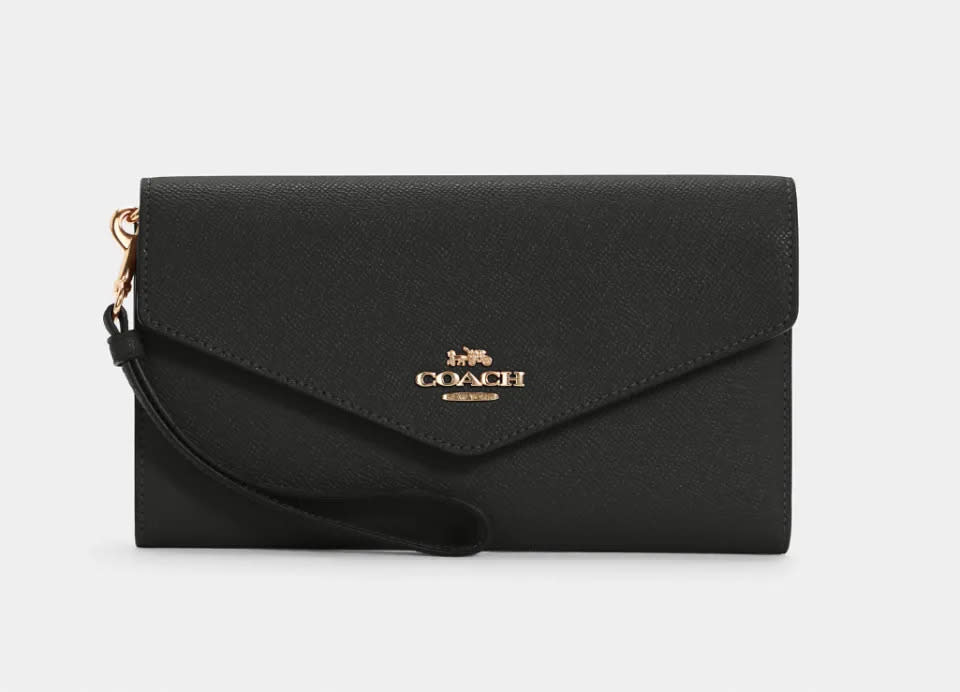 Cartera de mano Travel tipo sobre. Imagen vía Coach Outlet.