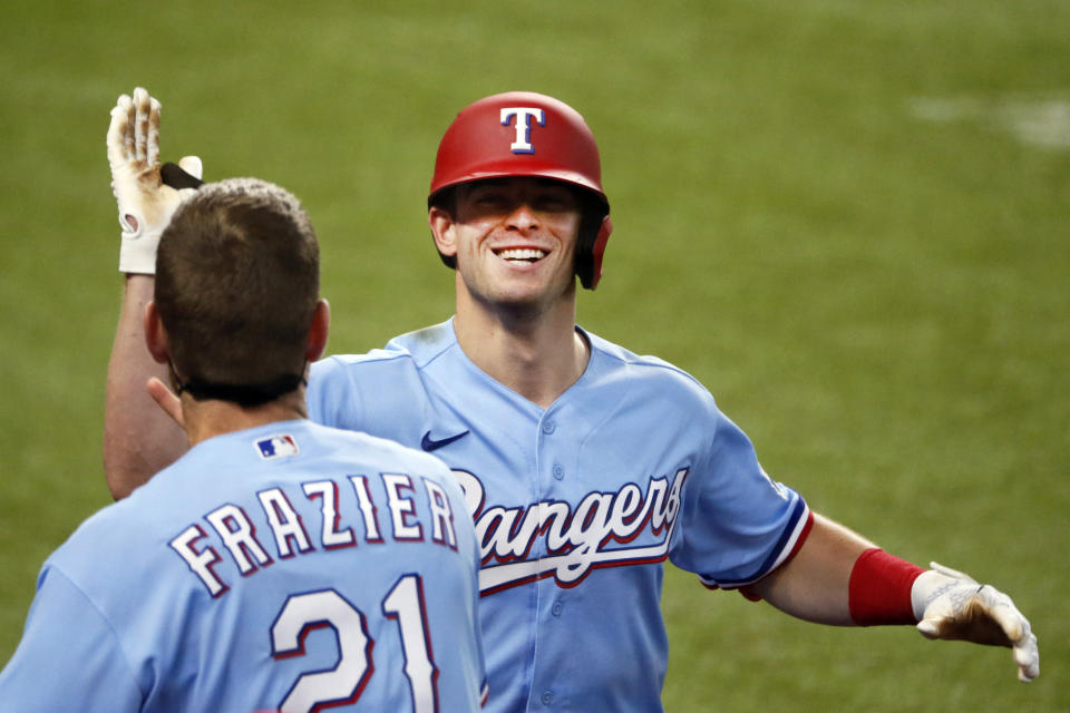 Texas Rangers' Nick Solak, right, is greeted at the dugout by Todd Frazier, left, after hitting a solo home run on a fly ball that the popped out of the mitt of Los Angeles Angels right fielder Jo Adell (not pictured) and went over the outfield wall during the fifth inning of a baseball game in Arlington, Texas, Sunday, Aug. 9, 2020. (AP Photo/Ray Carlin)