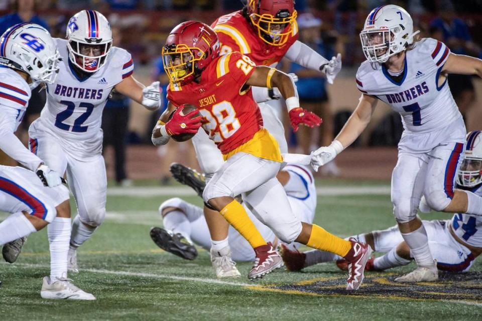 Jesuit’s Johnnie Brannon IV (28) runs the ball against Christian Brothers in the Holy Bowl in 2022 at Hughes Stadium.