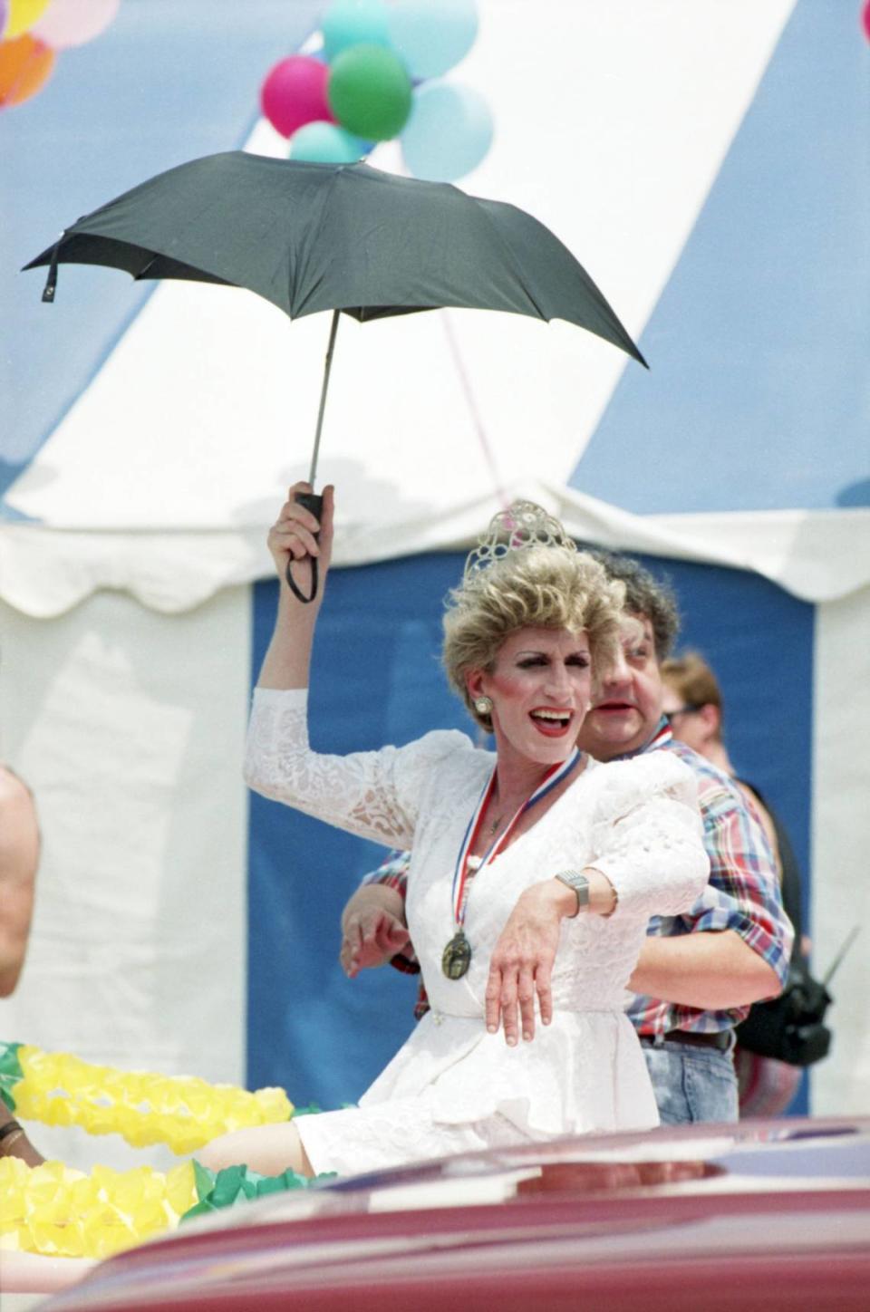 Los grandes mariscales Jerry 'Big Mama" Cassidy, a la derecha, y la drag queen Raina Lea (Gary Taylor), que lleva un paraguas, viajan en un Lincoln Continental descapotable rosa de 1958 durante el desfile de la Semana del Orgullo Gay de 1990 celebrado en Fort Worth.