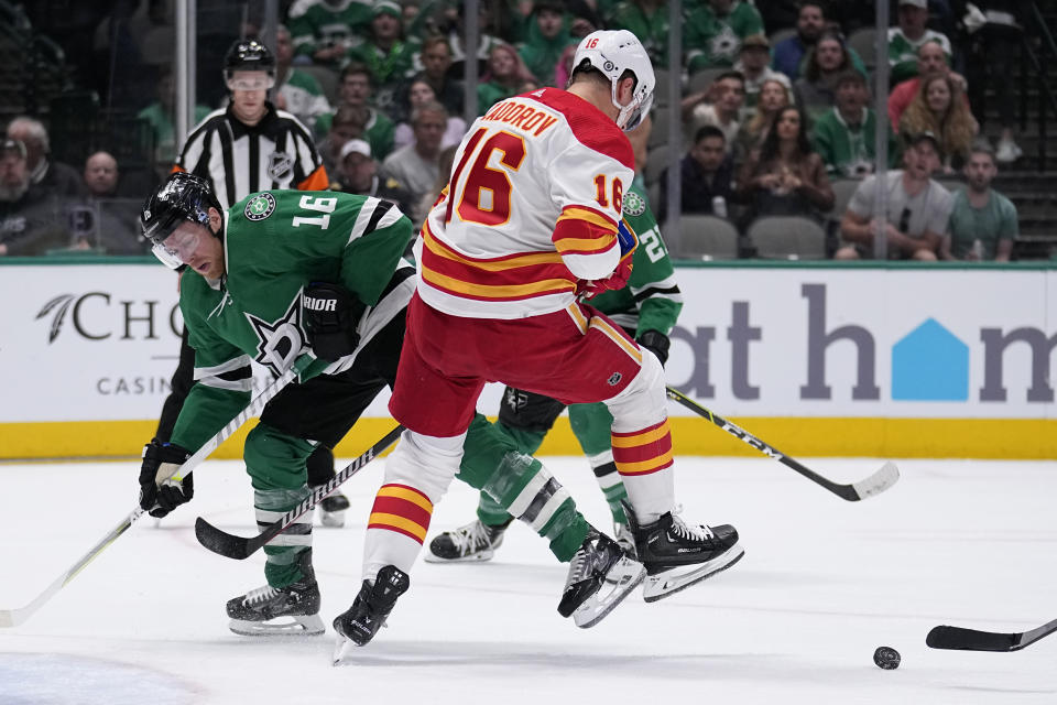 Dallas Stars' Joe Pavelski, left, and Calgary Flames' Nikita Zadorov, right, compete for control of the puck in the first period of an NHL hockey game, Monday, March 6, 2023, in Dallas. (AP Photo/Tony Gutierrez)