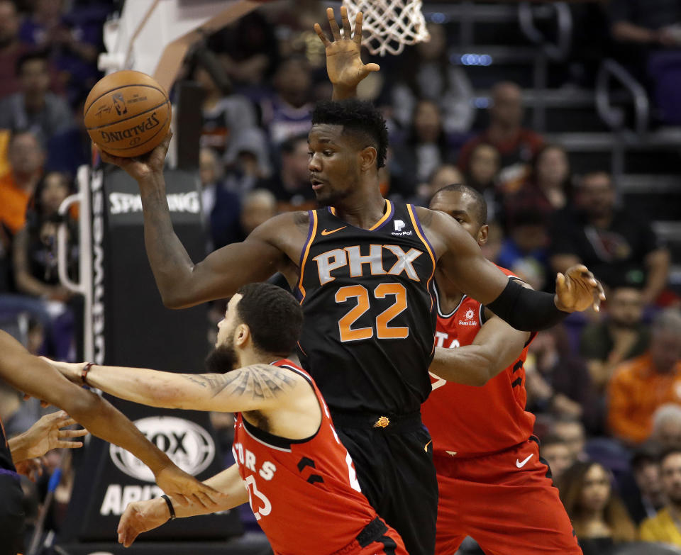 Phoenix Suns center Deandre Ayton (22) looks to pass as Toronto Raptors forward Serge Ibaka, right, and guard Fred VanVleet (23) defend during the first half of an NBA basketball game, Friday, Nov. 2, 2018, in Phoenix. (AP Photo/Matt York)