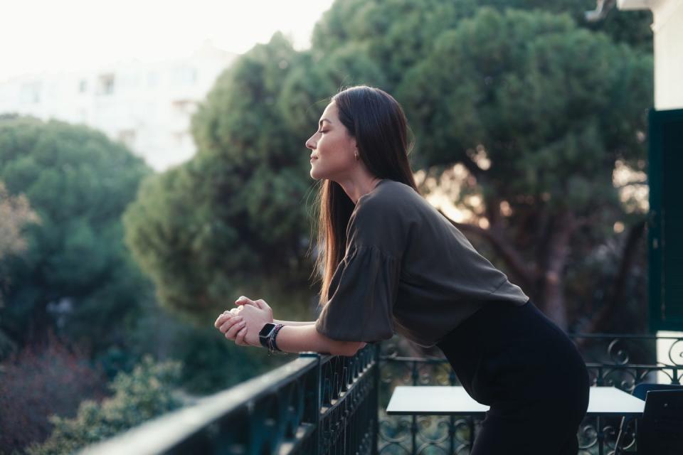 happy woman breathing deep fresh air at sunset on the balcony