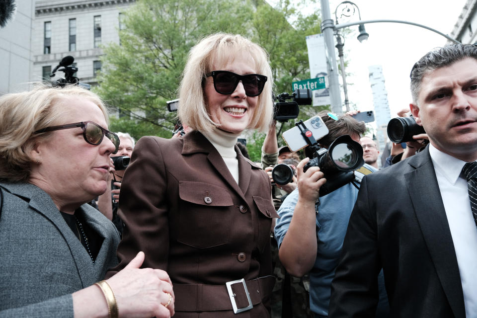 E. Jean Carroll with her lawyers looking triumphant, surrounded by the media.