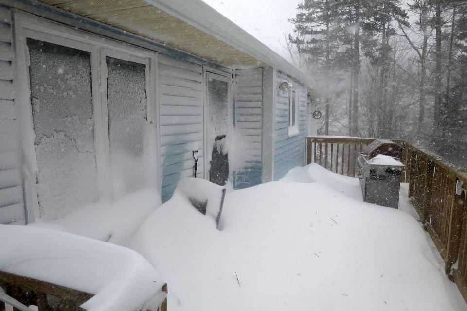 Blowing snow buries most of a deck and half a house during a blizzard in February 2017.