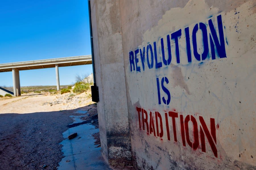 “Revolution is Tradition” appear freshly stenciled on a cement wall, Tuesday, April 9, 2024, in Mesquite, NV beneath a freeway overpass where armed protesters and federal government agents stared each other down through rifle sights 10 years ago. (AP Photo/Ty ONeil)