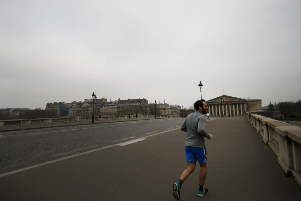 A man crosses an empty bridge as he jogs in Paris, Friday, March 20, 2020. French President Emmanuel Macron said that for 15 days people will be allowed to leave the place they live only for necessary activities such as shopping for food, going to work or taking a walk. For most people, the new coronavirus causes only mild or moderate symptoms. For some it can cause more severe illness, especially in older adults and people with existing health problems. (AP Photo/Christophe Ena)