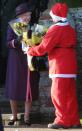 <p>A very happy Queen Elizabeth accepts flowers from a fan dressed as Santa Claus.</p>