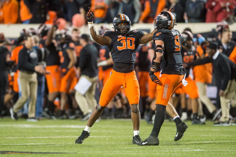 Oklahoma State defensive end Collin Oliver (30) and defensive end Brock Martin (9) celebrate after defeating Oklahoma at Boone Pickens Stadium.