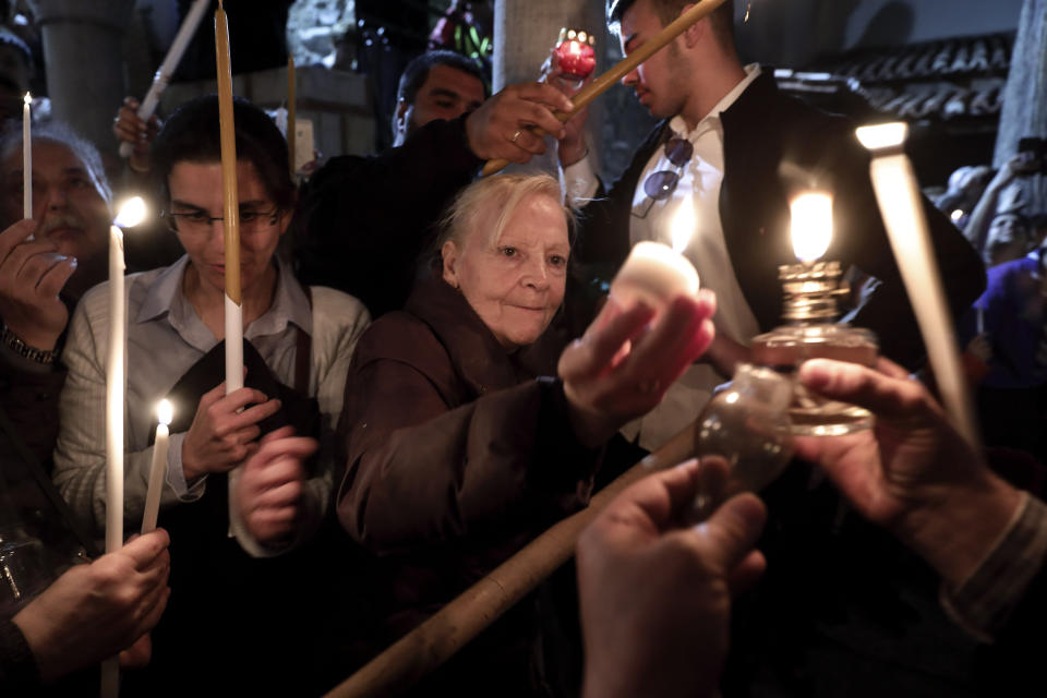 Orthodox faithful light their candles with "Holy Fire" brought from Jerusalem, at a church in Athens, on Saturday, April 27, 2019. A lantern carrying a flame lit in Jerusalem's Holy Sepulcher Church was welcomed in Greece with honors reserved for visiting heads of state. But a senior cleric boycotted the ceremony, miffed that the "Holy Flame" did not land within his see.(AP Photo/Yorgos Karahalis)