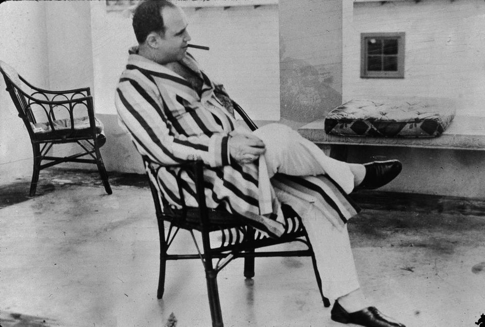 American gangster Al Capone (“Scarface”) (1899–1947) relaxes in his vacation home in Miami, 1930. Capone smokes a cigar and wears a striped dressing gown and slippers. (Photo by New York Times/Getty Images)