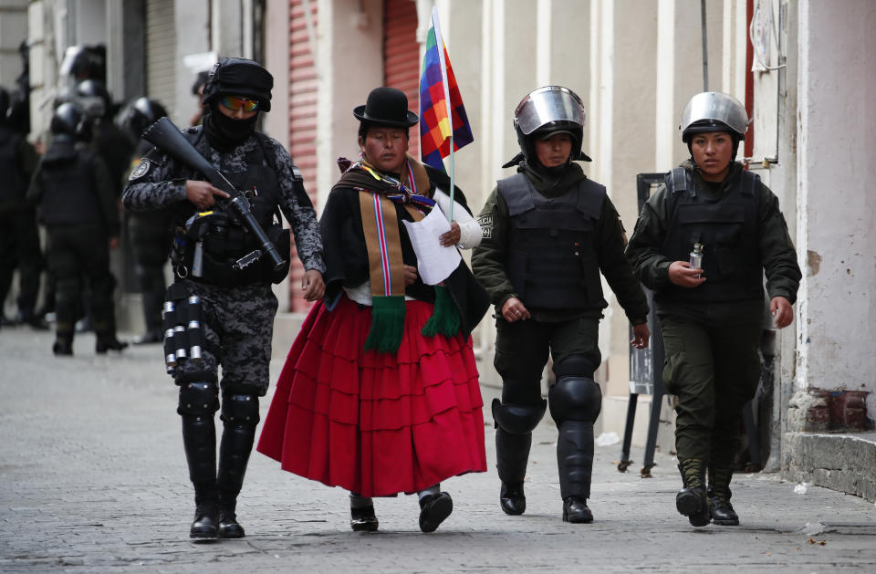 A supporter of Bolivia's former President Evo Morales is escorted by security forces to Congress, where she will turn in a petition in La Paz, Bolivia, Tuesday, Nov. 12, 2019. Morales, who transformed Bolivia as its first indigenous president, flew to exile in Mexico on Tuesday after weeks of violent protests, leaving behind a confused power vacuum in the Andean nation. (AP Photo/Natacha Pisarenko)