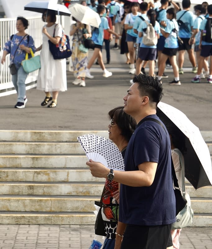 高雄地區高溫炎熱（1） 全台各地27日天氣高溫炎熱，高雄市高溫資訊呈橙色 燈號，提醒民眾慎防熱傷害。高雄知名景點大港橋周 邊午後遊憩民眾不少，有人搧扇子解暑、有人撐傘遮 陽。 中央社記者董俊志攝  113年6月27日 