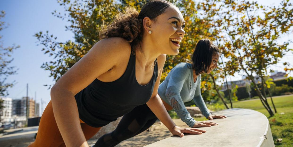 two women doing incline pushups in a park