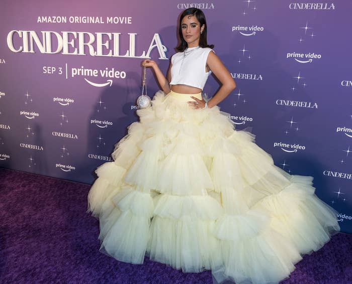 Camila, hand on hip and holding a small disco ball clutch in the other, wearing a long, wide tulle skirt