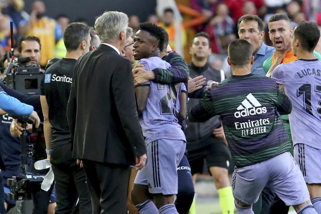 Real Madrid's Vinicius Junior, centre, walks past head coach Carlo Ancelotti, front left, after being sent off the pitch during a Spanish La Liga soccer match between Valencia and Real Madrid, at the Mestalla stadium in Valencia, Spain, Sunday, May 21, 2023. The game was temporarily stopped when Vinicius said a fan had insulted him from the stands. He was later sent off after clashing with Valencia players. (AP Photo/Alberto Saiz)