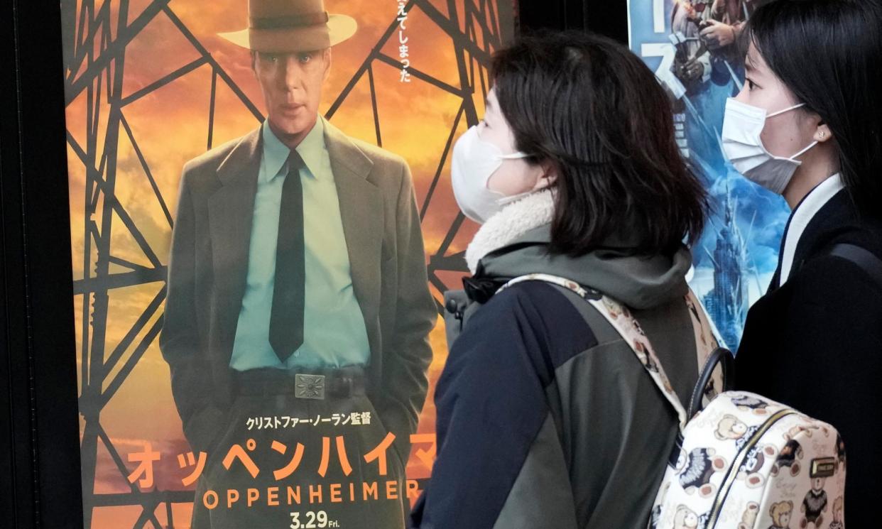 <span>People walk by a poster promoting Oppenheimer in Tokyo on Friday.</span><span>Photograph: Eugene Hoshiko/AP</span>