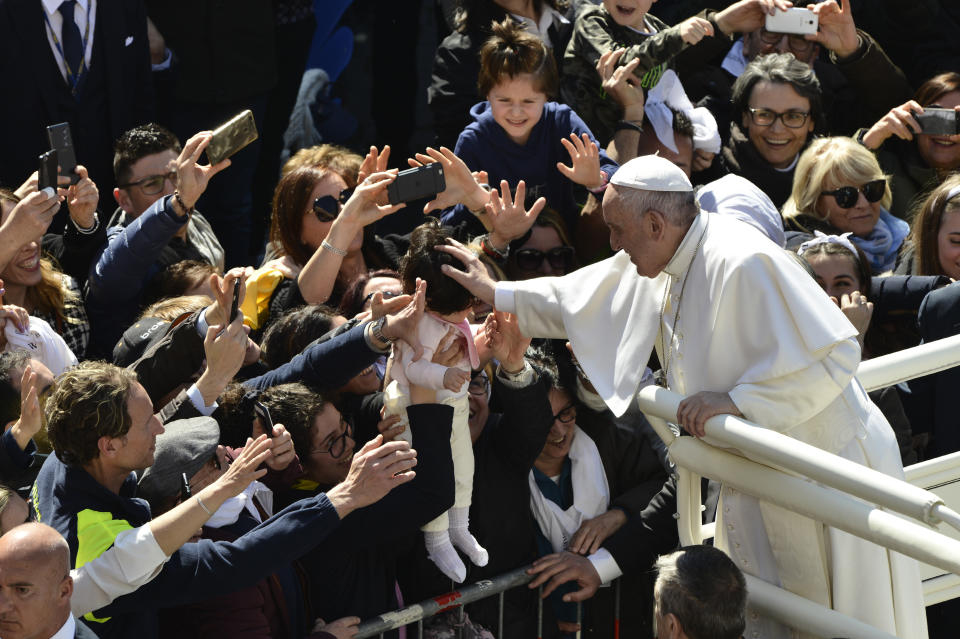 Faithful hand a baby to Pope Francis to bless upon his arrival at Loreto's cathedral, central Italy, Monday, March 25, 2019. Francis has traveled to a major Italian pilgrimage site dedicated to the Virgin Mary to sign a new document dedicated to today's youth. (AP Photo/Sandro Perozzi)