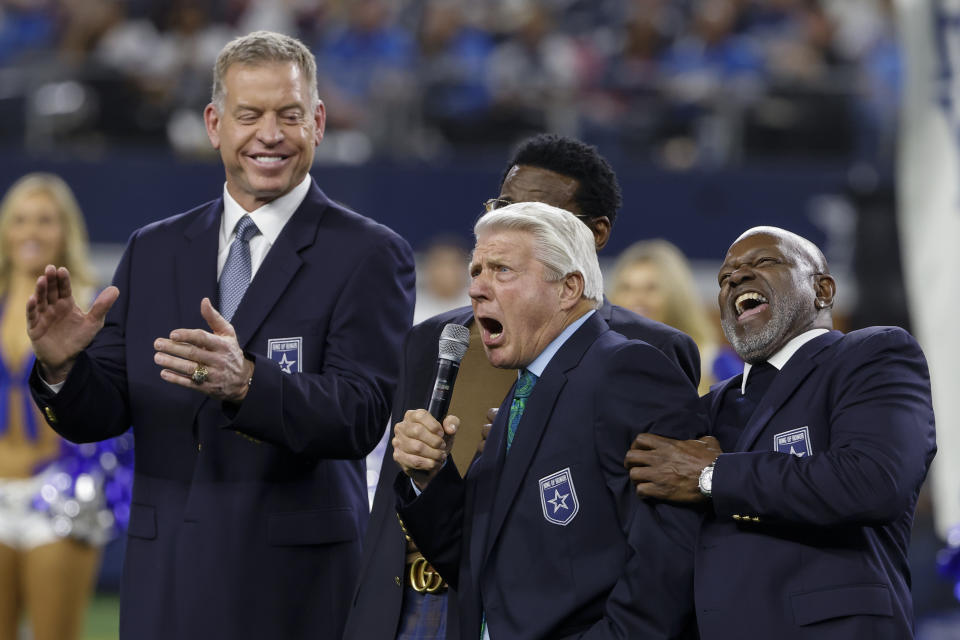 Pro Football Hall of Fame coach Jimmy Johnson, second from right, reacts while speaking next to his former players, from left, Troy Aikman, Michael Irvin and Emmit Smith during a ceremony inducting Johnson into the team's ring of honor at halftime of an NFL football game between the Cowboys and the Detroit Lions, Saturday, Dec. 30, 2023, in Arlington, Texas. (AP Photo/Michael Ainsworth)