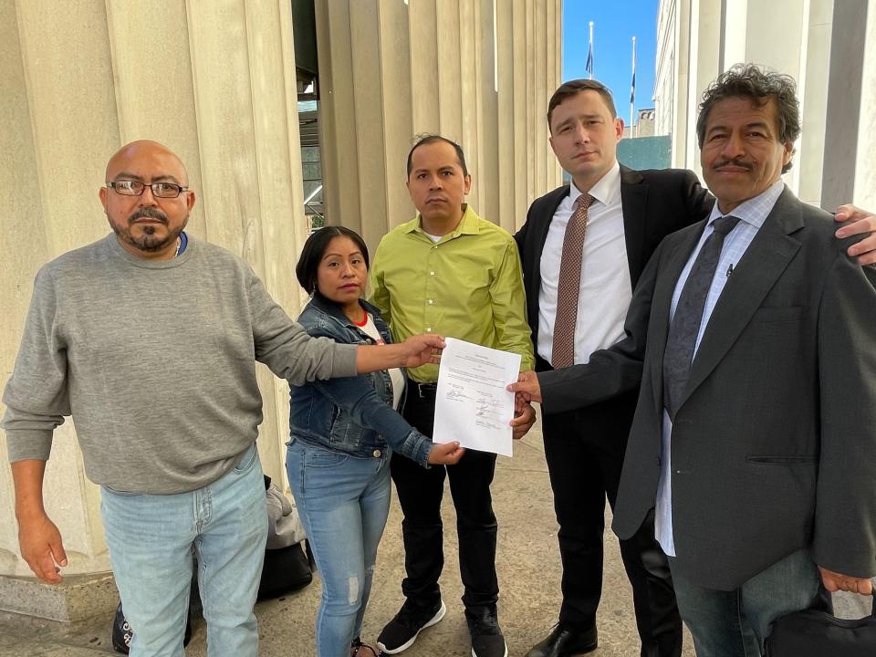 Plaintiffs and their lawyer pose with the document indicating their suit against Donald Trump , his campaign and security has been settled