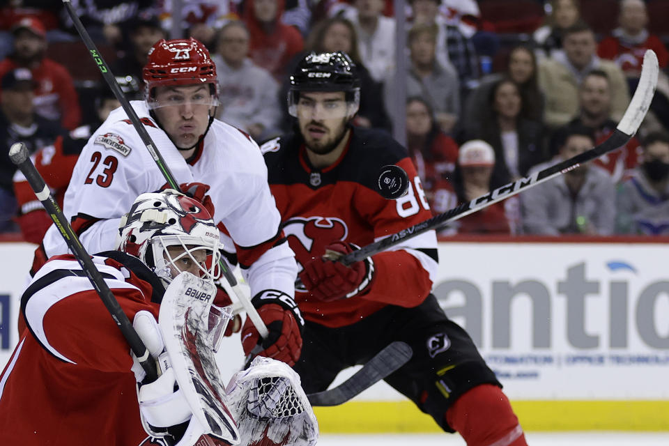New Jersey Devils goaltender Vitek Vanecek, front left, makes a save in front of Carolina Hurricanes right wing Stefan Noesen (23) during the third period of an NHL hockey game, Sunday, March 12, 2023, in Newark, N.J. (AP Photo/Adam Hunger)