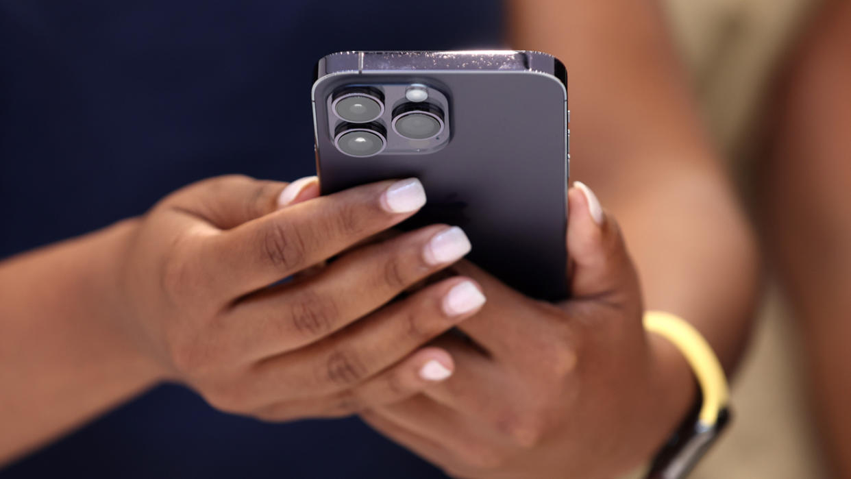 A woman holding an Apple iPhone 14 Pro.