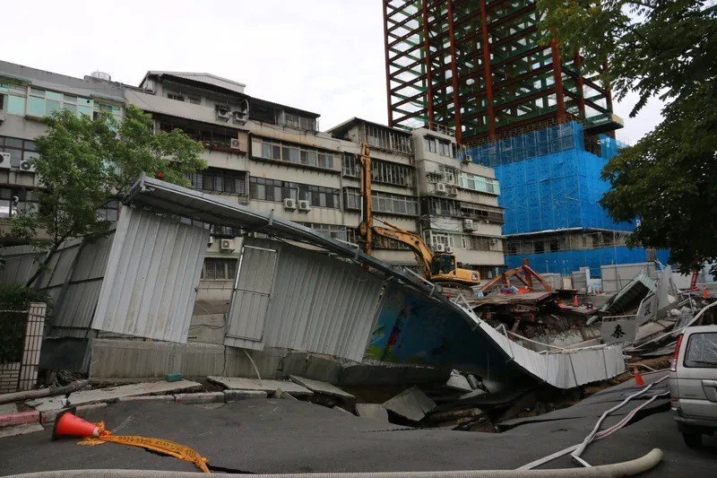 台北市中山區大直街巷弄多棟大樓疑因周邊建案開挖 而傾斜，記者8日走訪現場，發現傾斜民宅後方為一 建築工地，出現塌陷、圍籬傾倒等狀況，工程車不停 進出，針對塌陷處灌漿，要讓壓力先維持平衡，避免 讓房屋再次嚴重傾斜。 中央社記者劉建邦攝 112年9月8日