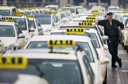 A taxi driver listens to speeches by his colleagues, during an Europe-wide protest of licensed taxi drivers against taxi hailing apps that are feared to flush unregulated private drivers into the market, in front of the Olympic stadium in Berlin, June 11, 2014. REUTERS/Thomas Peter