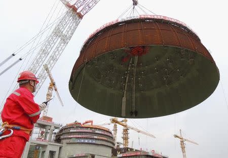 A worker looks on as the dome roof of a generator unit is lifted to be installed, at Tianwan Nuclear Power Plant, in Lianyungang, Jiangsu province, China, September 26, 2015. REUTERS/Stringer