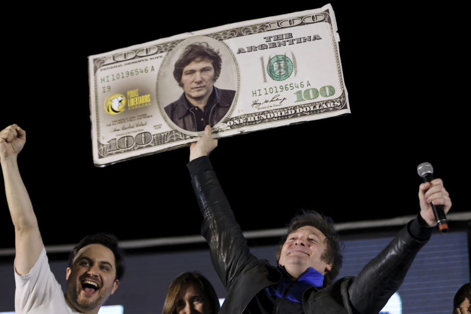 Javier Milei, Liberty Advances coalition presidential candidate, holds a cardboard image of a 100 US dollar bill bedecked with an image of his his face during his closing campaign rally in Cordoba, Argentina, Thursday, Nov. 16, 2023. Milei will face Economy Minister Sergio Massa, the ruling party's candidate, in a runoff election on Nov. 19. (AP Photo/Nicolas Aguilera)