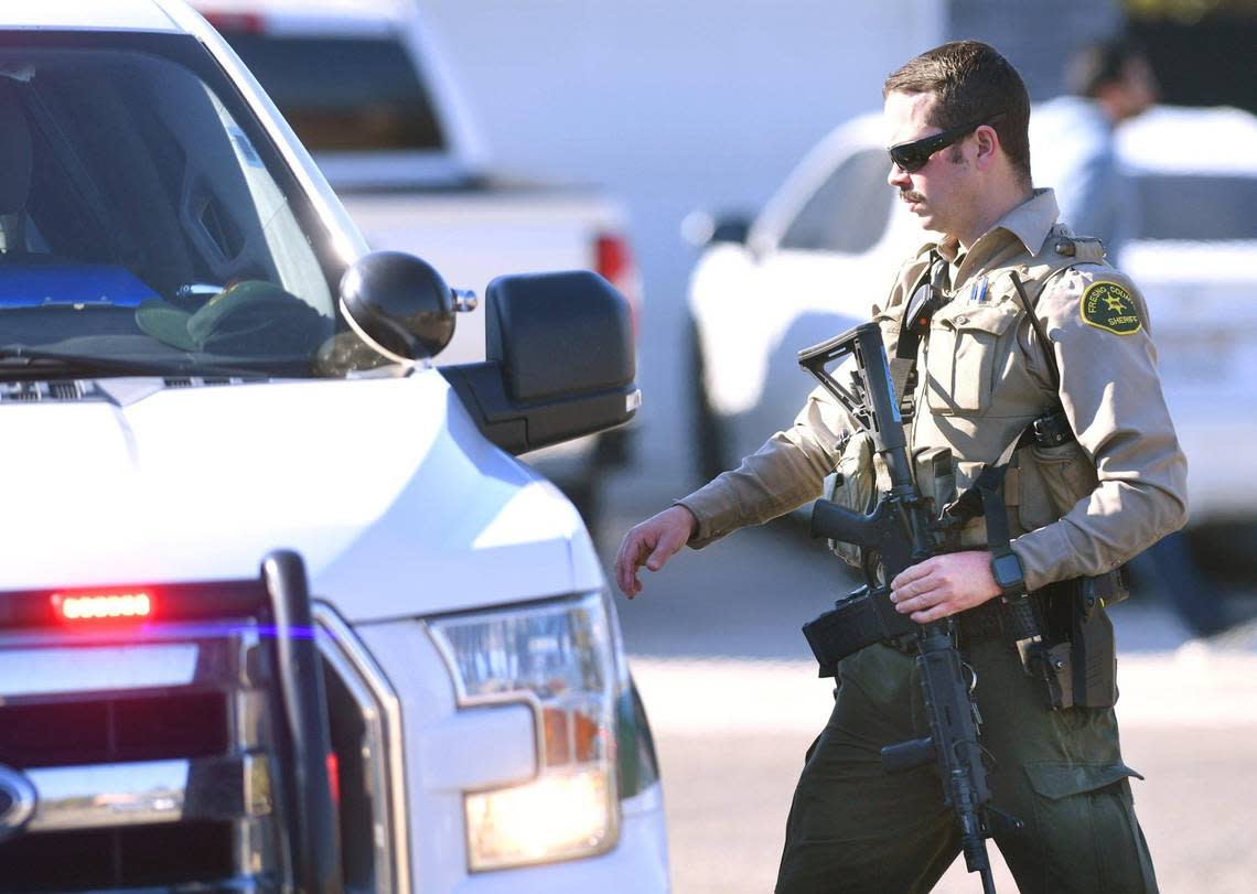 A Fresno County Sheriff deputy carries his weapon towards his vehicle near Eric White Elementary School after a shooting incident nearby Tuesday, Jan. 31, 2023 in Selma.