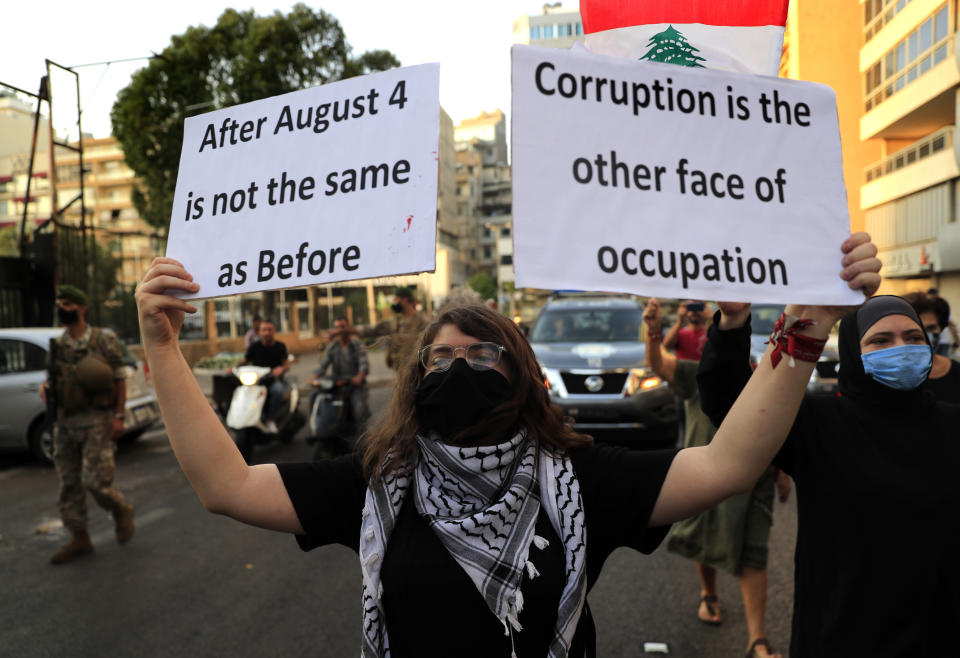 A Lebanese activist holds up placards as she marches during a protest near the Parliament speaker house to demand answers and justice for the victims of the August 4 explosion that hit the seaport, in Beirut, Lebanon, Tuesday, Oct. 20, 2020. The blast was one of the largest non-nuclear explosions in history and six months later, political and confessional rivalries have undermined the probe into the Beirut port explosion and brought it to a virtual halt, mirroring the same rivalries that have thwarted past attempts to investigate political crimes throughout Lebanon's history. (AP Photo/Hussein Malla)