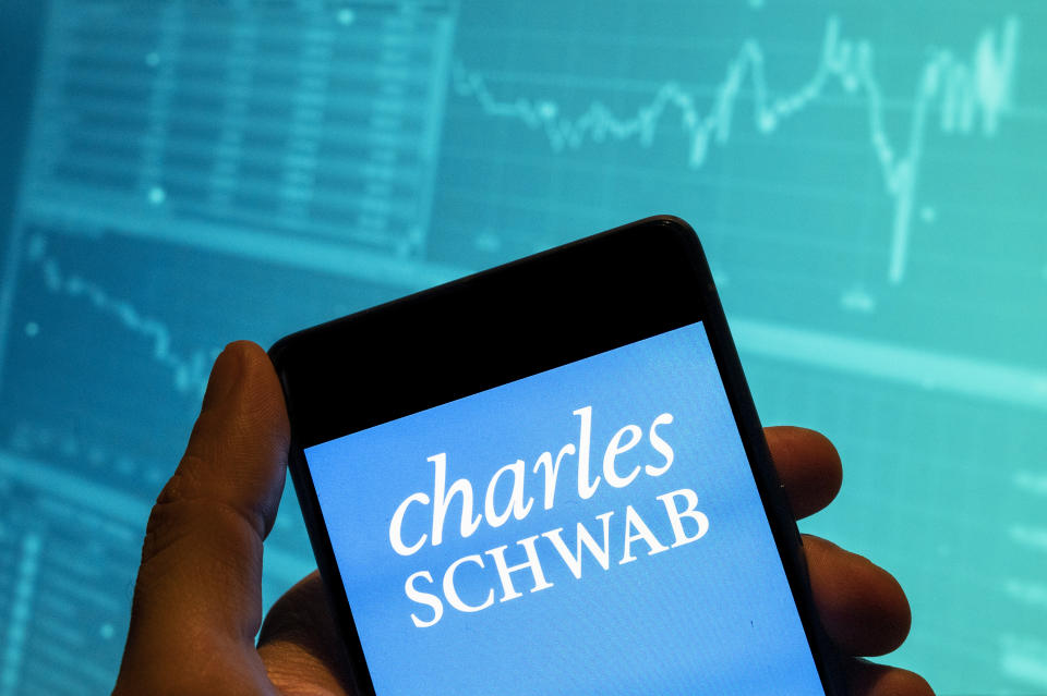 KÍNA – 2023/02/19: Ezen a fotóillusztráción a Charles Schwab amerikai multinacionális pénzügyi szolgáltató cég logója látható egy okostelefonon, a háttérben gazdasági tőzsdeindex grafikonnal. (Fotóillusztráció: Budrul Chukrut/SOPA Images/LightRocket a Getty Images segítségével)