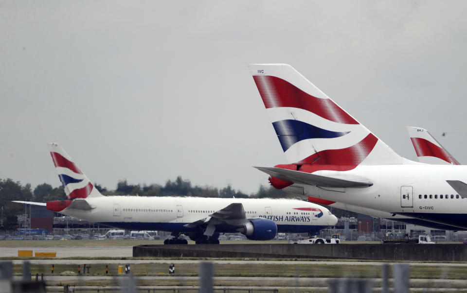 FILE - In this Monday, Sept. 9, 2019 file photo, a British Airways plane, at left, is towed past other planes sitting parked at Heathrow Airport in London. British Airways says flights are being disrupted by a “technical issue.” Information from Heathrow, Britain’s busiest airport, shows some trans-Atlantic flights delayed Thursday Nov. 21, 2019 by several hours. (AP Photo/Matt Dunham, File)