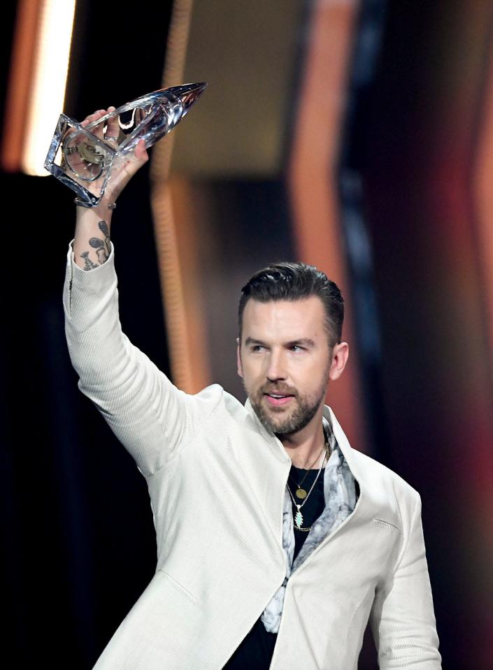 T.J. Osborne holds up the award for Vocal Duo of the Year during the 55th CMA Awards at Bridgestone Arena Wednesday, Nov. 10, 2021 in Nashville, Tenn.