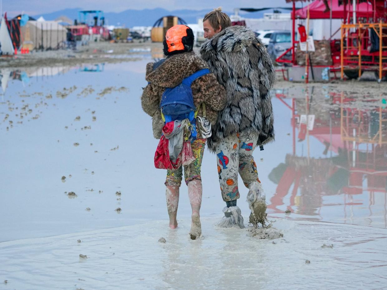 Two Burning Man attendees stand in mud and water.
