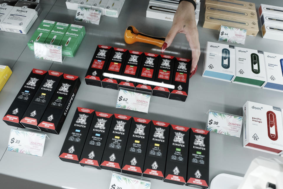 This Tuesday, Sept. 10, 2019, photo shows a bud tender arranging a display of Kingpen cannabis vape cartridges at the Cannery Cannabis store in Los Angeles. Bootleggers eager to profit off unsuspecting consumers are mimicking popular vape brands, pairing replica packaging churned out in Chinese factories with untested, and possibly adulterated, cannabis oil produced in the state's vast underground market. (AP Photo/Richard Vogel)