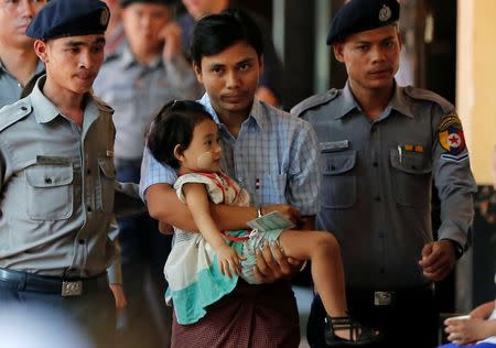 Detained Reuters journalist Kyaw Soe Oo is escorted by police as he holds his daughter while arriving for a court hearing in Yangon, Myanmar May 9, 2018. REUTERS/Stringer